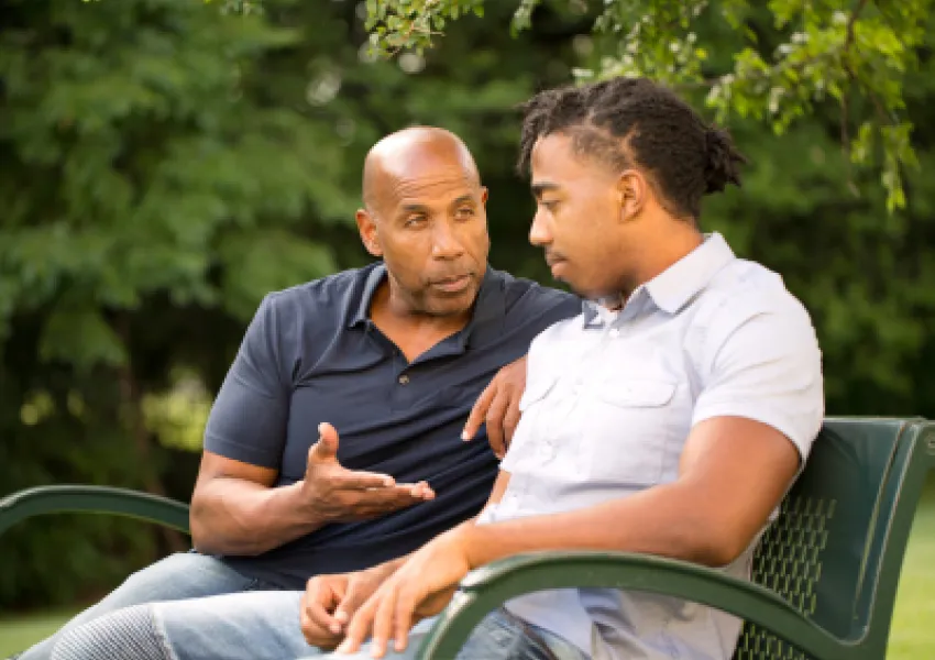 two men sat on a bench, having a conversation