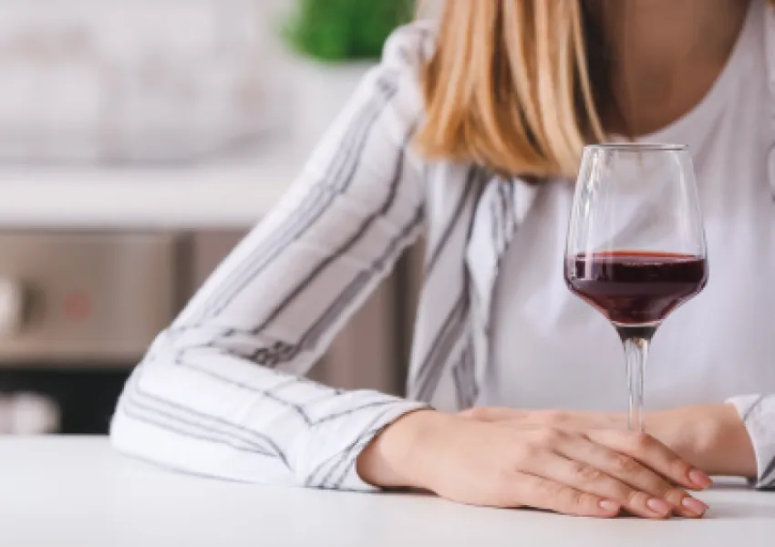 Woman holding glass of red wine, face not visible