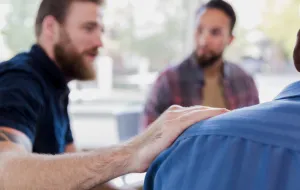 man with arm on shoulder of other man