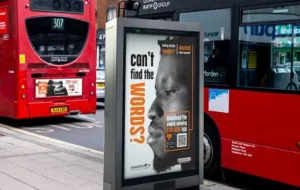 An on-street advertising display board featuring the stay alive campaign ('can't find the words?' + the side profile of a man's face), with two red London in the background
