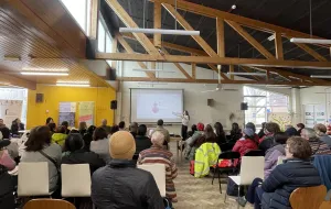 Picture of group listening to a female speaker delivering a presentation.