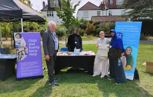 People infront of a stand displaying information about childhood vaccinations.