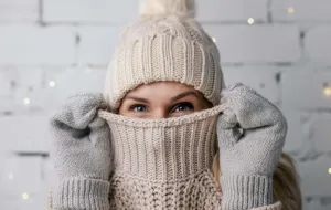 A person wearing winter clothing including a bobble hat and gloves.