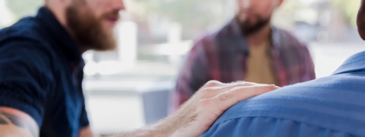 man with arm on shoulder of other man