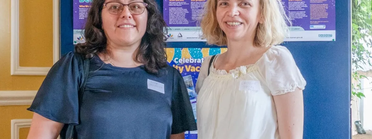 Alida and Cecilia posing in front of community vaccine champions poster display