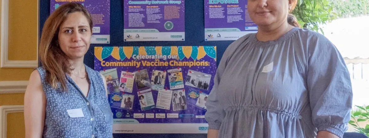 Community Network Group posing in front of poster display of the community vaccine champion case studies 