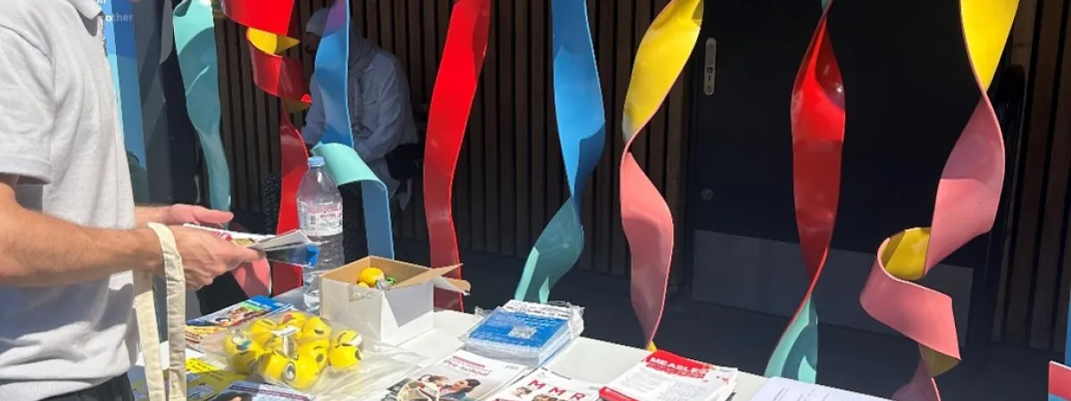 Person at a stall holding a totebag and looking at the vaccination information provided.