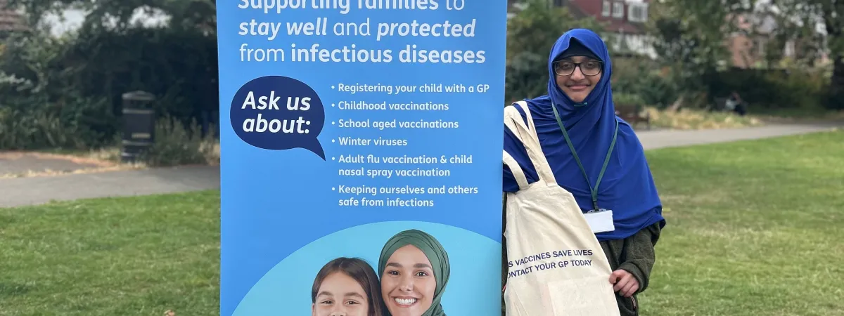 Person infront of a banner displaying information about childhood vaccinations.