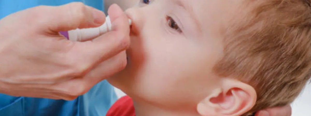 A toddle receiving a nasal spray