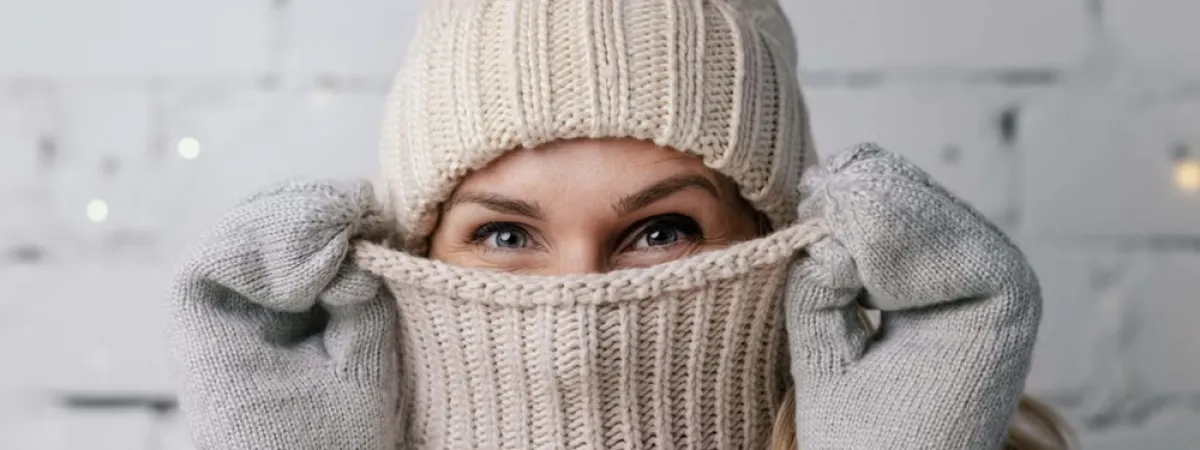 A person wearing winter clothing including a bobble hat and gloves.